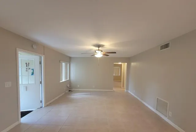 an empty room with windows and fan