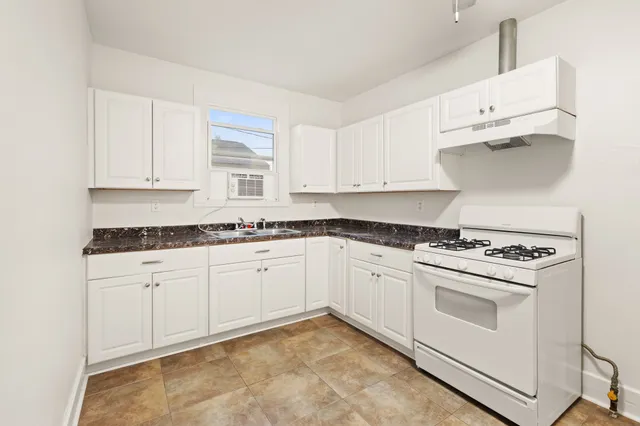 a kitchen with granite countertop white cabinets and white appliances