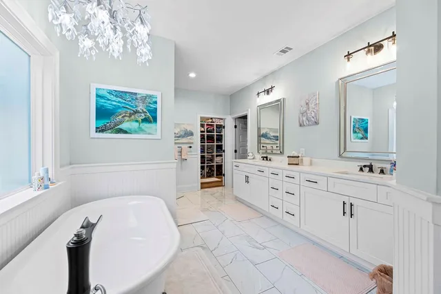 a spacious bathroom with double vanity sink a two mirror a window and a bathtub