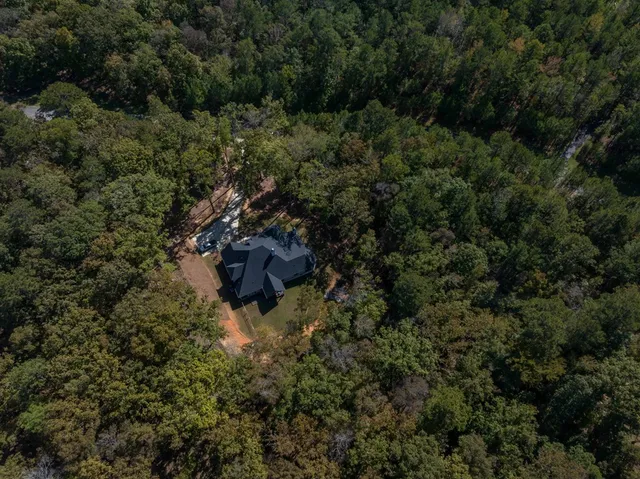 an aerial view of residential house with outdoor space and trees all around