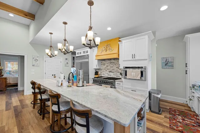 a view of a dining room and livingroom with furniture wooden floor a chandelier
