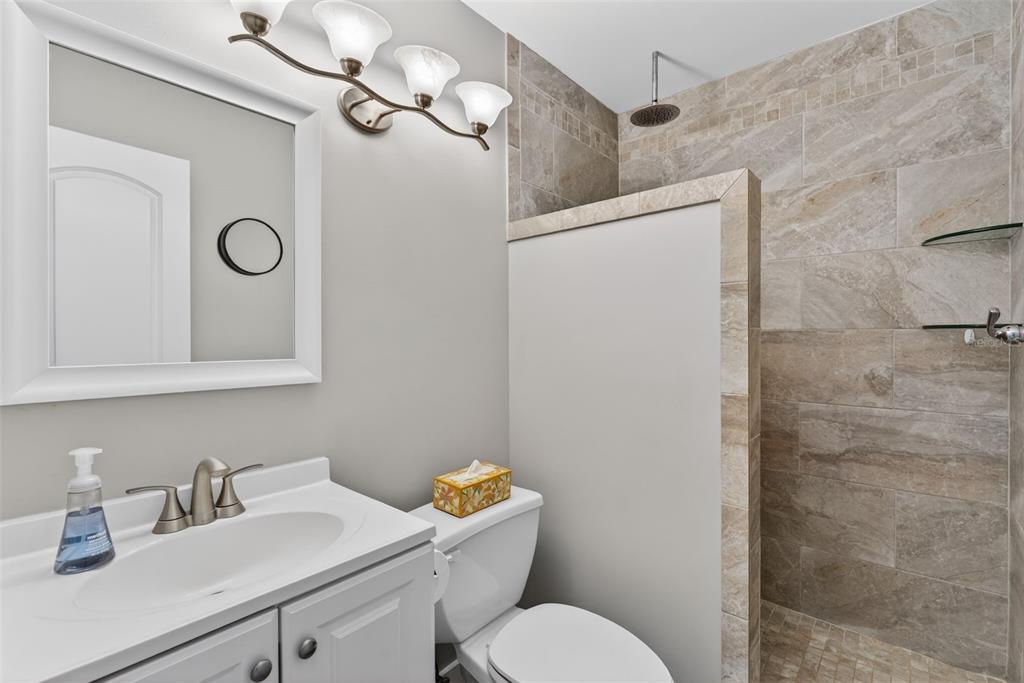 1632 Stickney Point Road, Unit 201 Sarasota, FL 34231 - Photo 18 of 43 a bathroom with a toilet sink vanity and mirror