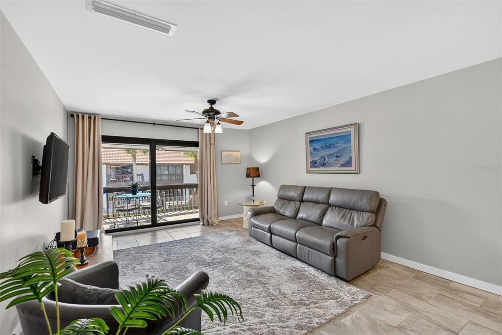 1632 Stickney Point Road, Unit 201 Sarasota, FL 34231 - Photo 7 of 43 a living room with furniture a flat screen tv and a floor to ceiling window