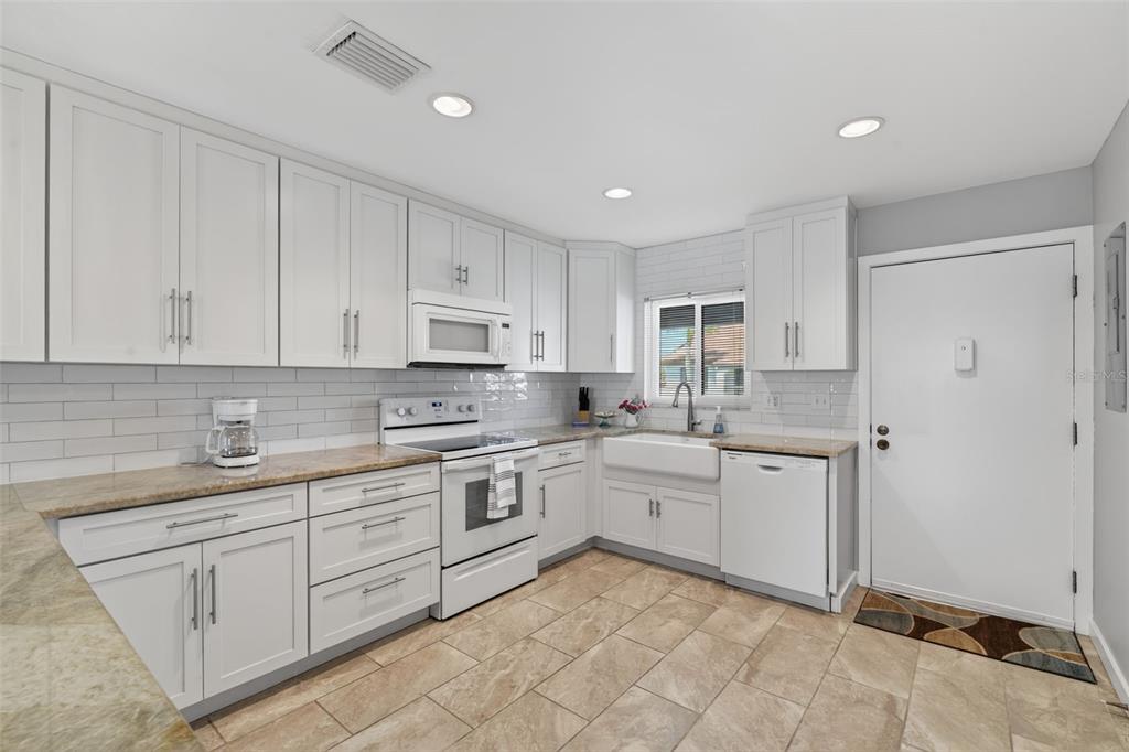 1632 Stickney Point Road, Unit 201 Sarasota, FL 34231 - Photo 9 of 43 a kitchen with white cabinets sink and stove