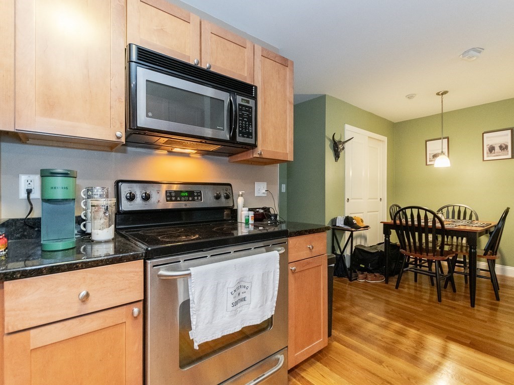48 Coffey Street, Unit 5B Boston, MA 02122 - Photo 12 of 31 a kitchen with stainless steel appliances granite countertop a stove a microwave a sink a dining table and chairs