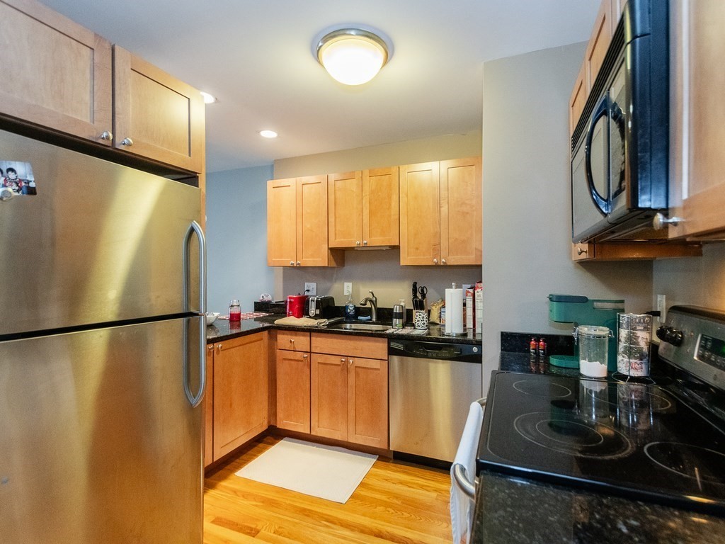 48 Coffey Street, Unit 5B Boston, MA 02122 - Photo 10 of 31 a kitchen with granite countertop a refrigerator a stove a sink dishwasher and a microwave with wooden floor