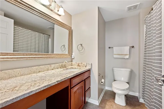 a bathroom with a granite countertop toilet sink and mirror