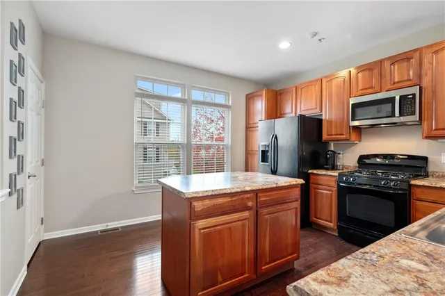 a kitchen with stainless steel appliances granite countertop a stove a sink dishwasher a refrigerator and a microwave oven with wooden floor