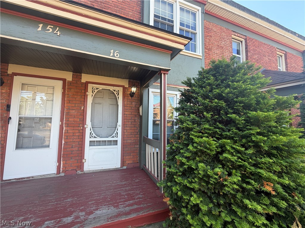 15416 Waterloo Road Cleveland, OH 44110 - Photo 2 of 18 Brick facade building featuring a covered porch with a painted wood floor and white screen doors