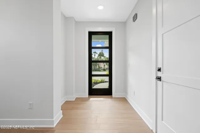 a view of an empty room with window and wooden floor