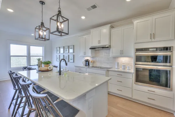a kitchen with stainless steel appliances granite countertop a stove top oven a sink dishwasher a dining table and chairs with wooden floor