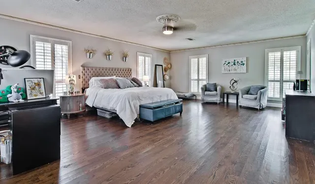 a spacious bedroom with a bed and wooden floor