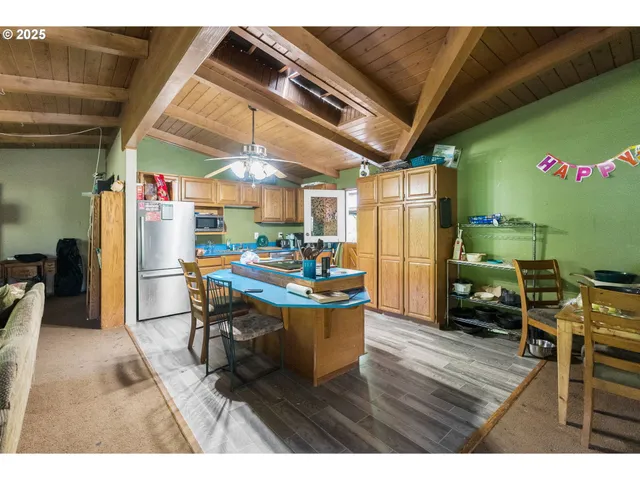 a kitchen with stainless steel appliances kitchen island granite countertop a table chairs and a refrigerator