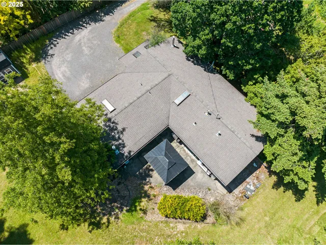 an aerial view of a house with a yard and trees all around