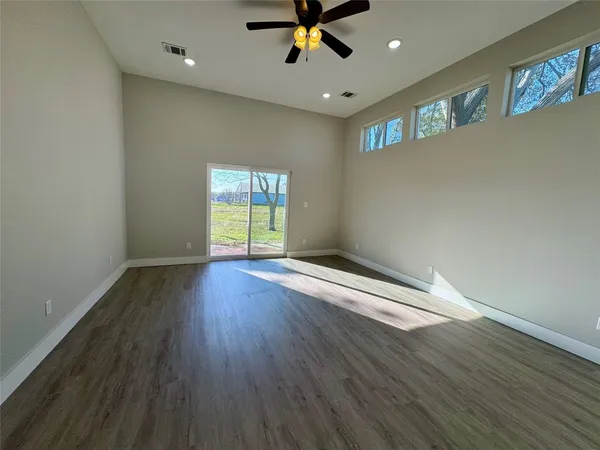 an empty room with wooden floor and windows