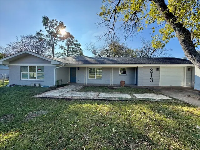 a view of a house with a yard and large tree