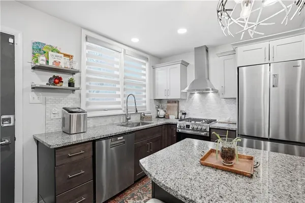 a kitchen with stainless steel appliances granite countertop a sink dishwasher stove and refrigerator with wooden cabinets