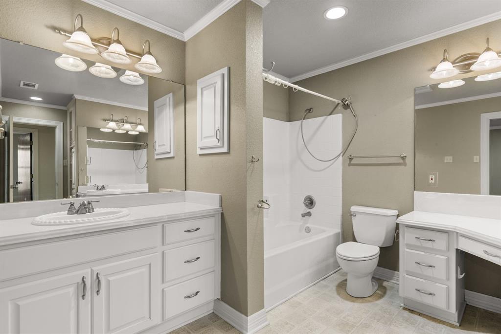 13539 Chapel Road Lorena, TX 76655 - Photo 17 of 37 Bathroom featuring a white vanity with integrated sink, white cabinetry with silver hardware, a bathtub with shower, a commode, and a separate vanity area with a built-in dressing table