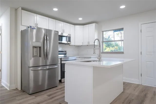 a kitchen with stainless steel appliances granite countertop a refrigerator a sink a stove a microwave and wooden floors