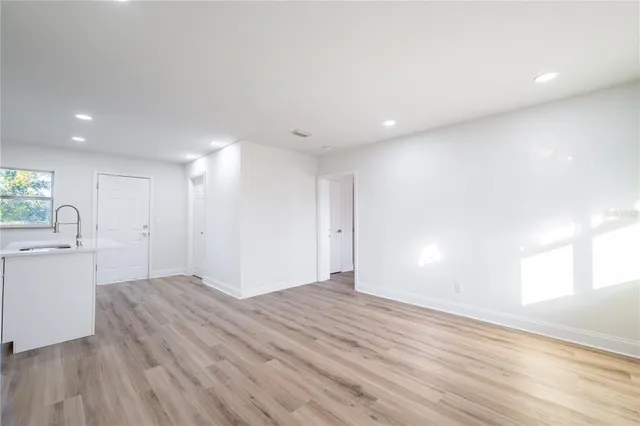 a view of an empty room with window and wooden floor