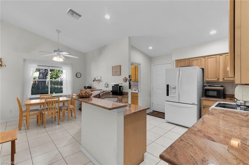 443 Dundee Court Naples, FL 34104 - Photo 22 of 39 a kitchen with white cabinets and refrigerator