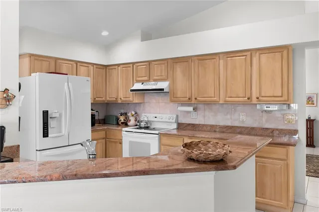 a kitchen with stainless steel appliances granite countertop a refrigerator sink and stove