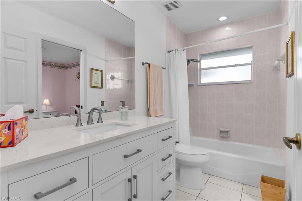 443 Dundee Court Naples, FL 34104 - Photo 32 of 39 a bathroom with a granite countertop sink a toilet mirror and bathtub