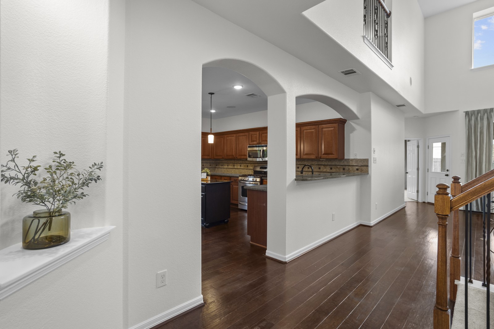 245 Razzmatazz Trail Buda, TX 78610 - Photo 6 of 37 Two-story foyer featuring dark wood-finish flooring, a wood and wrought iron staircase, arched doorways, a built-in wall niche, and a second-story window