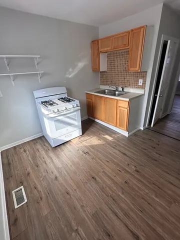 a kitchen with stainless steel appliances wooden floor and a refrigerator