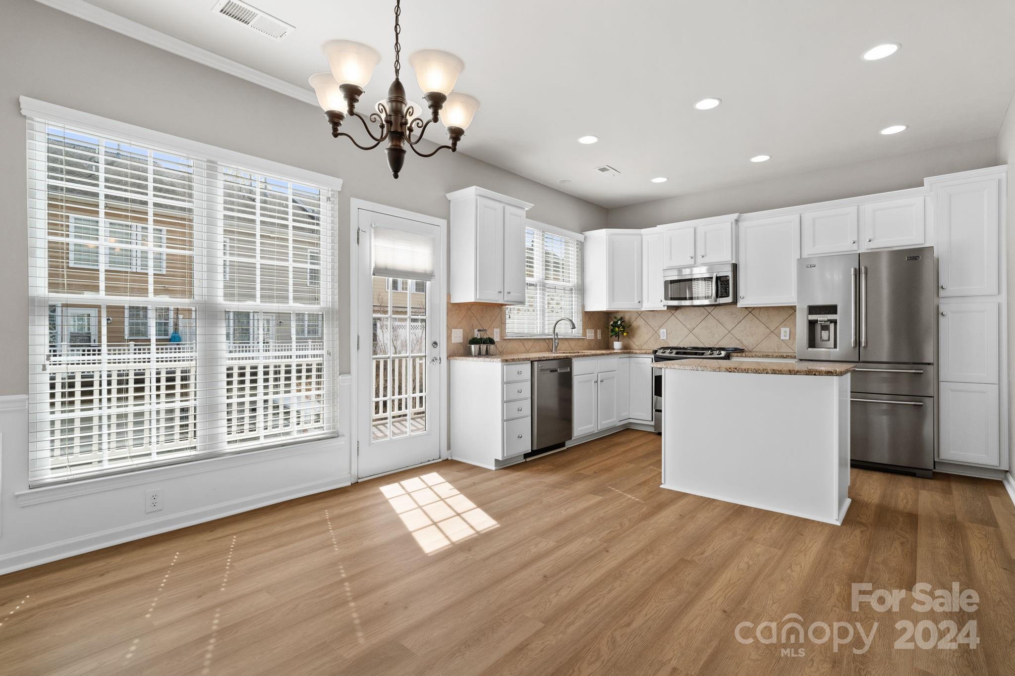 926 Lyndley Drive Fort Mill, SC 29708 - Photo 13 of 36 a kitchen with stainless steel appliances granite countertop a refrigerator a sink dishwasher a stove and white cabinets with wooden floor