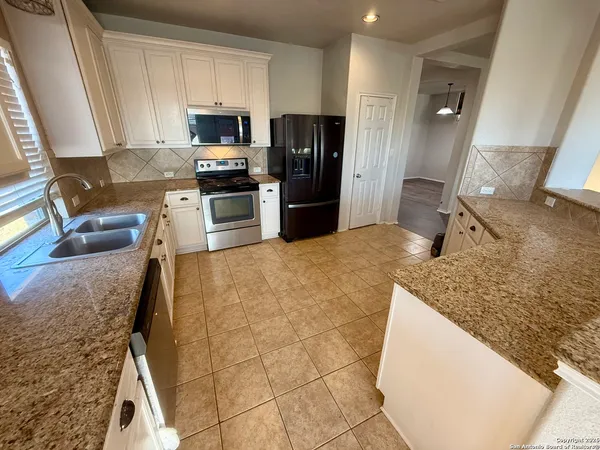 a kitchen with granite countertop a refrigerator a stove top oven a sink and dishwasher