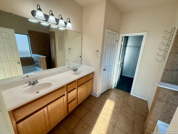 a spacious bathroom with a double vanity sink a large mirror and a shower