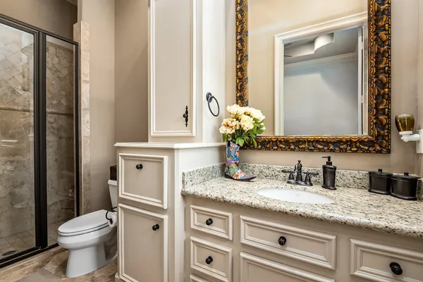 a bathroom with a granite countertop sink a toilet and a mirror