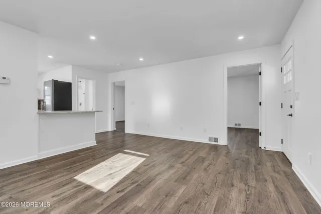 a view of empty room with wooden floor and windows