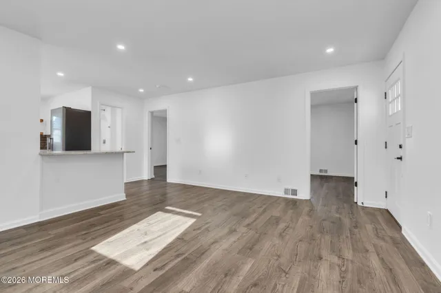 a view of empty room with wooden floor and windows