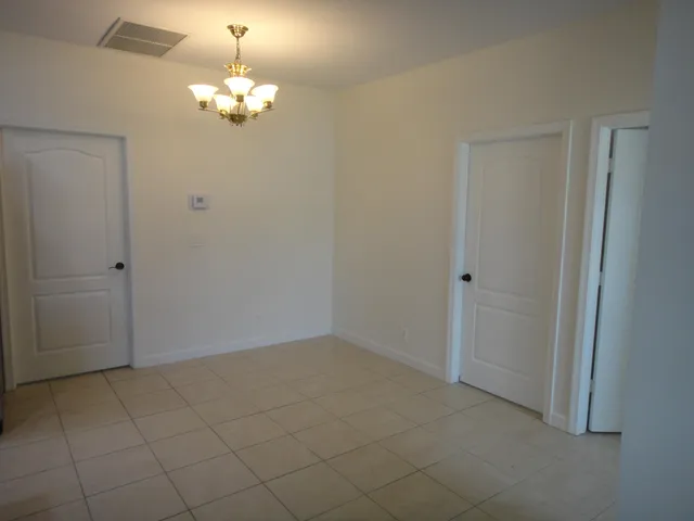 a view of an empty room with chandelier fan