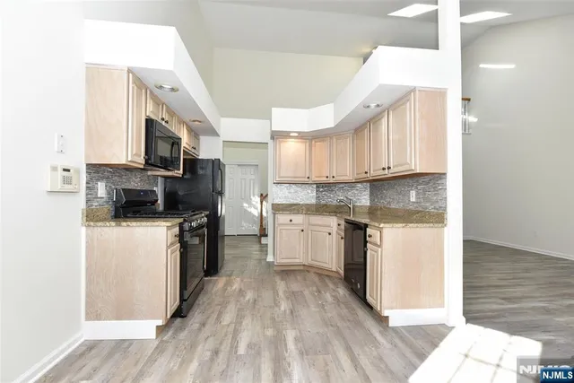 a kitchen with a refrigerator a stove top oven a sink and dishwasher with wooden floor