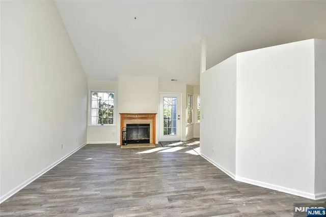 a view of empty room with wooden floor and fireplace