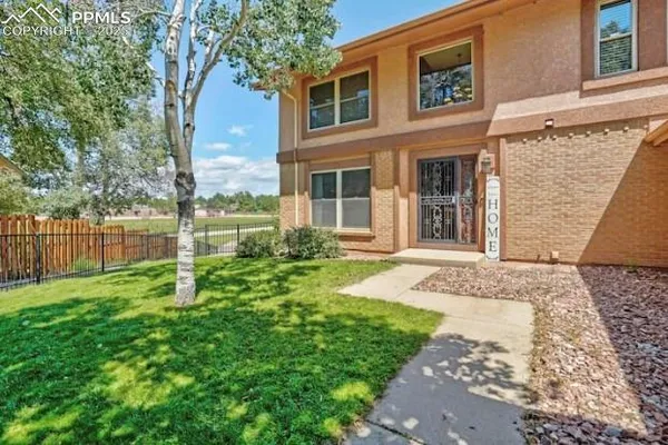 a view of a house with a yard and large tree