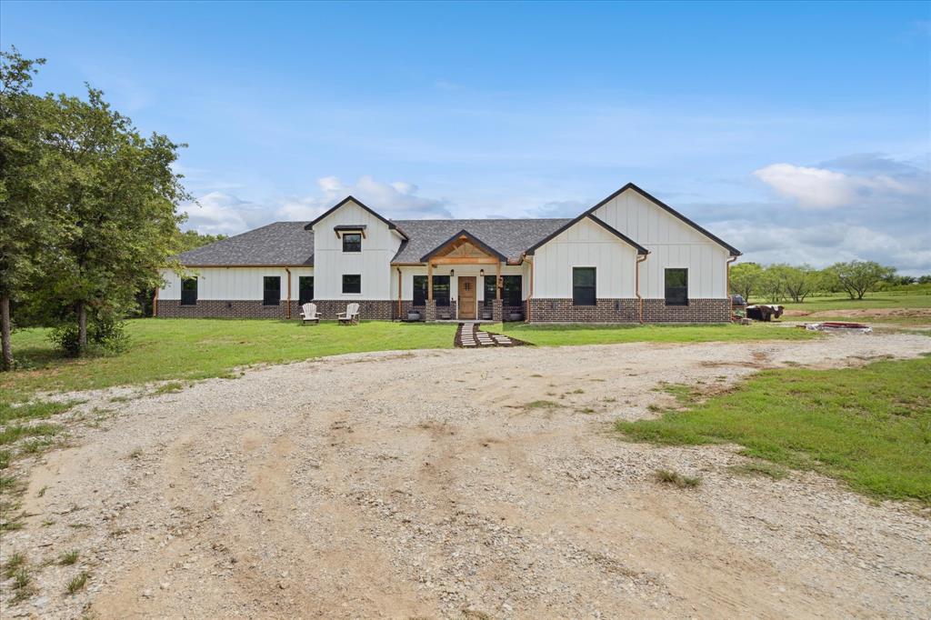 a view of house with a big yard and large trees