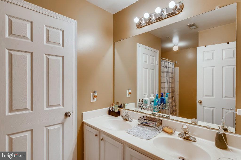 7410 Maury Road Windsor Mill, MD 21244 - Photo 15 of 28 a bathroom with a double vanity sink a mirror and a shower