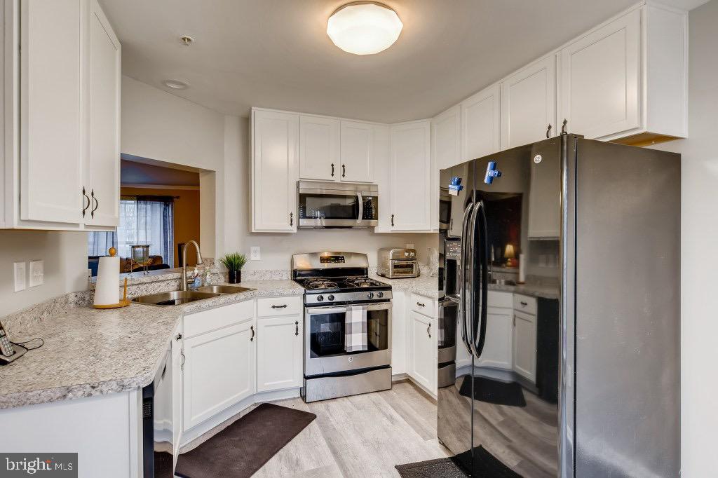 7410 Maury Road Windsor Mill, MD 21244 - Photo 7 of 28 a kitchen with a sink stainless steel appliances and white cabinets