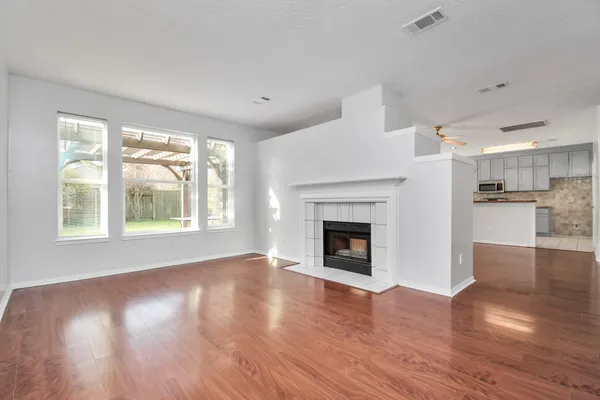 a view of an empty room with wooden floor and a window