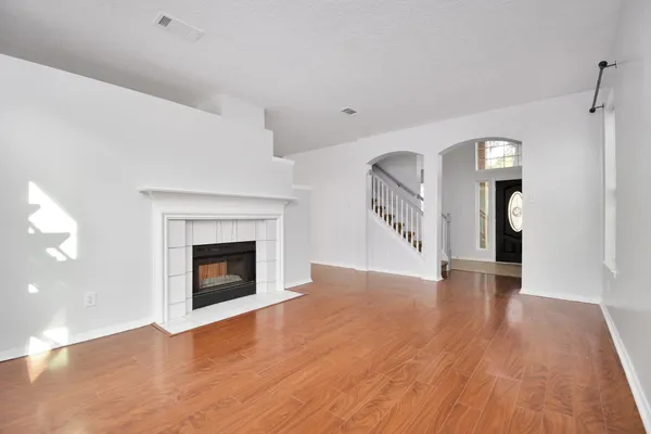 a view of an empty room with wooden floor fireplace and a window