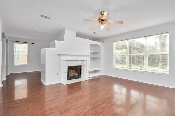 a view of an empty room with wooden floor and a window