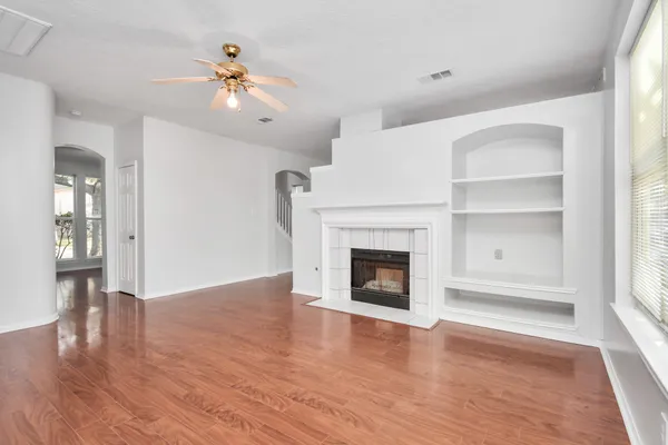 a view of an empty room with wooden floor fireplace and a window
