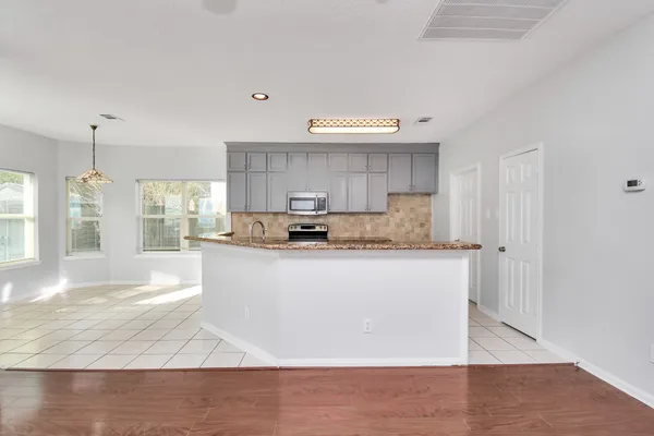 a large kitchen with granite countertop a stove a sink and a refrigerator