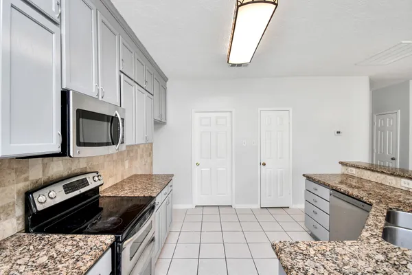 a kitchen with stainless steel appliances granite countertop a stove a sink and a microwave