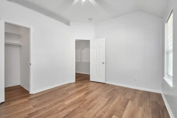 a view of an empty room with wooden floor and a window