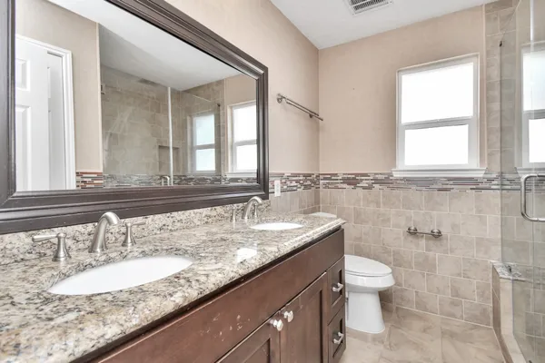 a bathroom with a granite countertop sink a toilet and a mirror